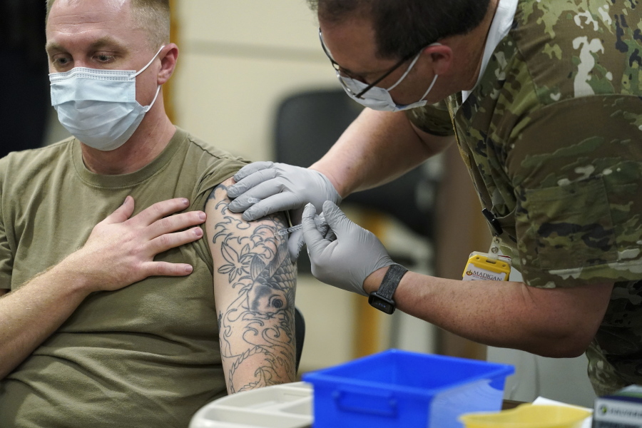 FILE - In this Dec. 16, 2020, file photo, Staff Sgt. Travis Snyder, left, receives the first dose of the Pfizer COVID-19 vaccine given at Madigan Army Medical Center at Joint Base Lewis-McChord in Washington state, south of Seattle. Nurse Jose Picart, right, administered the shot. Washington Gov. Jay Inslee on Thursday, June 17, 2021, announced a new COVID-19 vaccine incentive lottery for the state's military, family members and veterans because the federal government wasn't sharing individual vaccine status of those groups with the state and there were concerns they would be left out of a previously announced lottery. (AP Photo/Ted S.