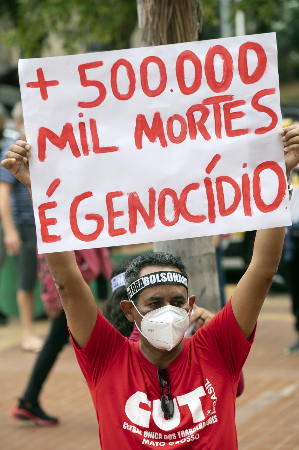 A man, wearing a protective face mask, holds a sign with a message that reads in Portuguese; "500,000 deaths is genocide", during a protest against Brazilian President Jair Bolsonaro and his handling of the pandemic and economic policies protesters say harm the interests of the poor and working class, in Cuiaba, Brazil, Saturday, June 19, 2021.
