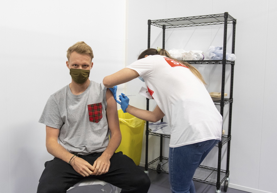 A man receives a dose of a COVID-19 vaccine, at a mass coronavirus vaccination centre held in Arsenal's Emirates Stadium, in north London, Friday June 25, 2021.