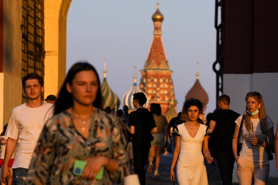 People, most of them without face masks, walk at Red Square during sunset in Moscow, Russia, Thursday, June 24, 2021. An ambitious plan of vaccinating 30 million Russians by mid-June against the coronavirus has fallen short by a third, and the country has started to see a surge in daily new infections.