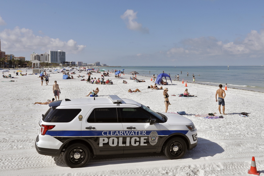 FILE - In this Monday, May 4, 2020 file photo, police officers patrol the area after Clearwater Beach officially reopened to the public in Clearwater Beach, Fla. Florida is among several states that amplified their 2021-2022 budgets with at least part of their share of a $195 billion state aid package from the recent American Rescue Plan Act signed by President Joe Biden. The state's record $101.5 billion budget is up roughly 11%, with bonuses for teachers, police and firefighters, and new construction projects at schools and colleges.