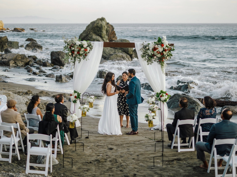 This photo shows bride Namisha Balagopal and groom Suhaas Prasad getting married in a small legal ceremony Aug. 15, 2020, on Muir Beach near San Francisco. The couple plans a larger traditional South Asian Indian wedding this August in Utah amid a boom in post-vaccination nuptials around the world.
