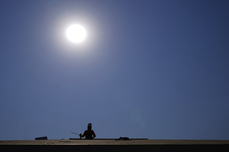 A roofer works on a new roof in a housing development while the sun beats down on him as the heat wave continues Thursday in Phoenix. (Ross D.