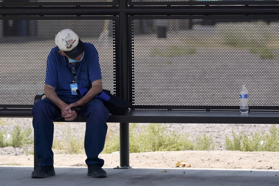 A person waits for a bus in the shade as the heat wave in the Western states continues Thursday, June 17, 2021, in Phoenix. (AP Photo/Ross D.