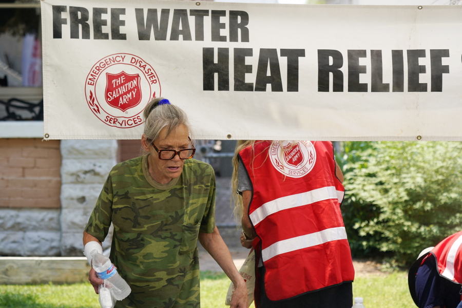 A pedestrian takes a bottle of water at a Salvation Army hydration station during a heatwave as temperatures hit 115-degrees, Tuesday, June 15, 2021, in Phoenix. (AP Photo/Ross D.