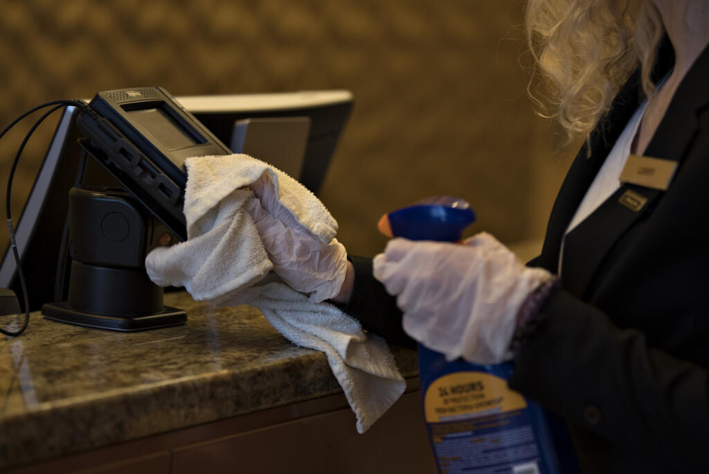Guest service agent Libby Lusk keeps the credit card machines at the front desk disinfected at the Hilton Vancouver in 2020.