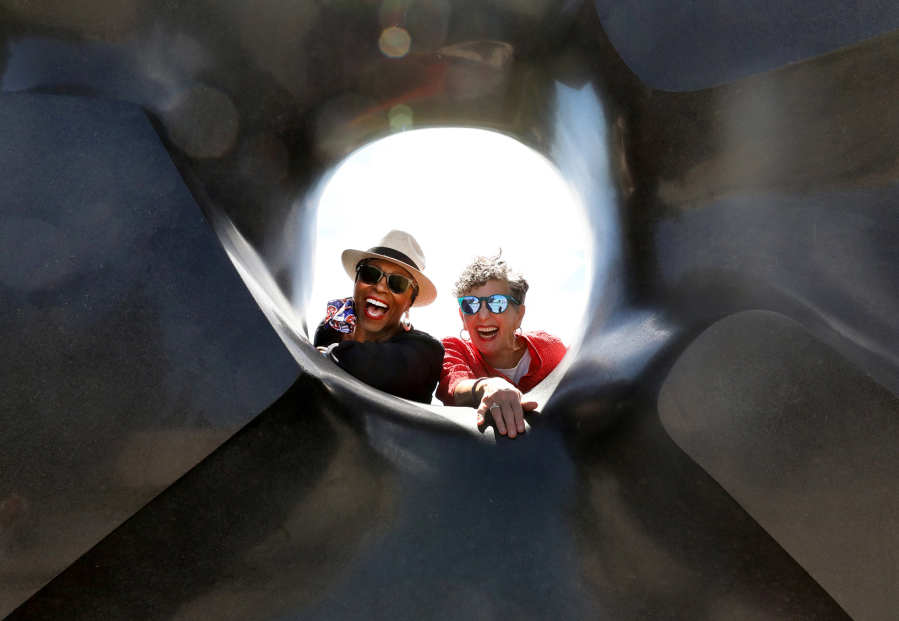 Vivian Phillips, left, and Marcie Sillman have teamed up to create a lively arts-based podcast called "DoubleXposure." Here, they're encircled by Isamu Noguchi's "lack Sun" sculpture in Volunteer Park in Seattle.