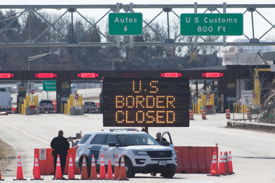 U.S. Customs officers stand beside a sign saying that the U.S. border is closed at the at Lansdowne, Ontario, on March 22, 2020.
