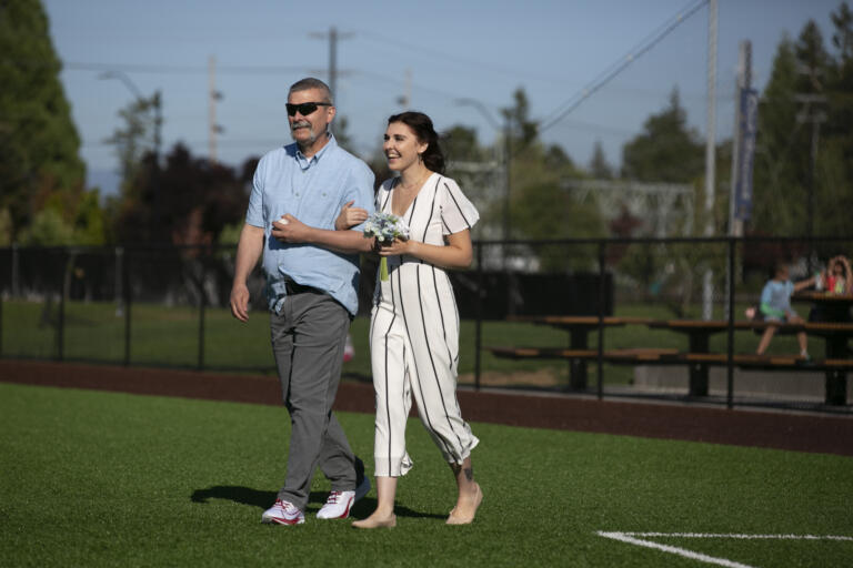 Erin Thum's father Robert Thum walks her out to the pitcher's mound to marry Eli Shubert at Ridgefield Outdoor Recreation Complex on Wednesday, July 14, 2021.