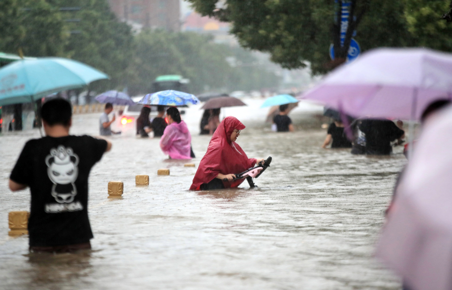 People walk in the flooded road after record downpours in Zhengzhou, in central China's Henan province, on July 20, 2021.