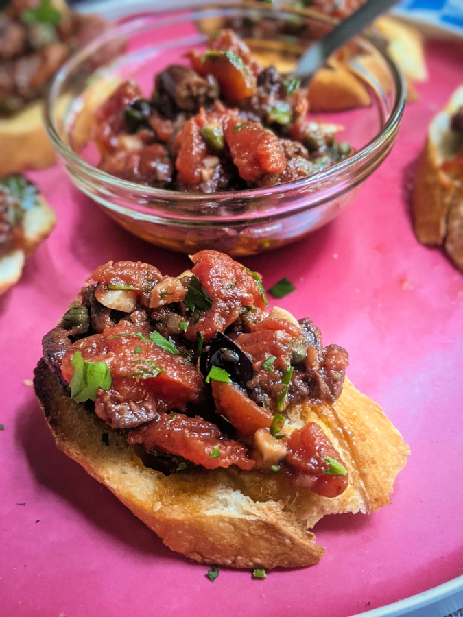 In this easy appetizer, crostini are topped with puttanesca, a spicy sauce made with tomato, capers, olives, garlic and anchovy.