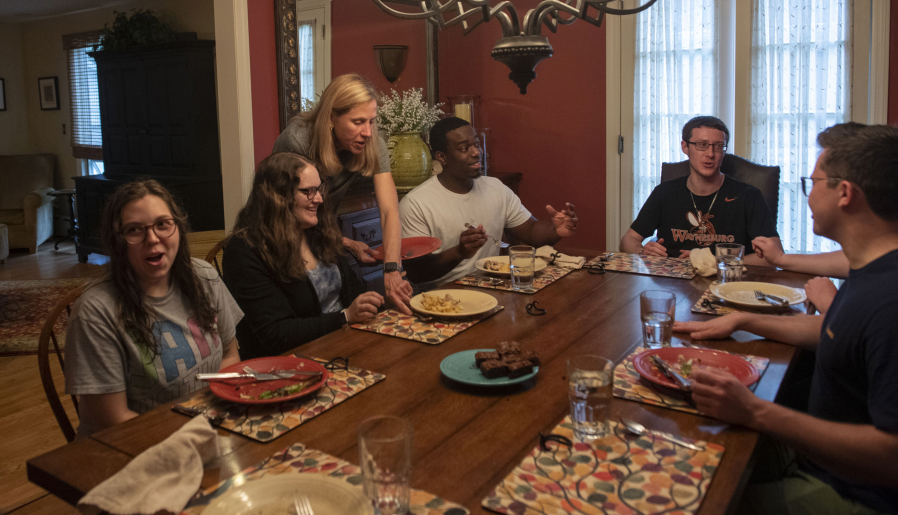 Julie McCormick, the director of the Pittsburgh Fellows program, takes a plate from the table on May 3 at her home in Sewickley, Penn. Every Monday, McCormick hosts a dinner for the fellows.