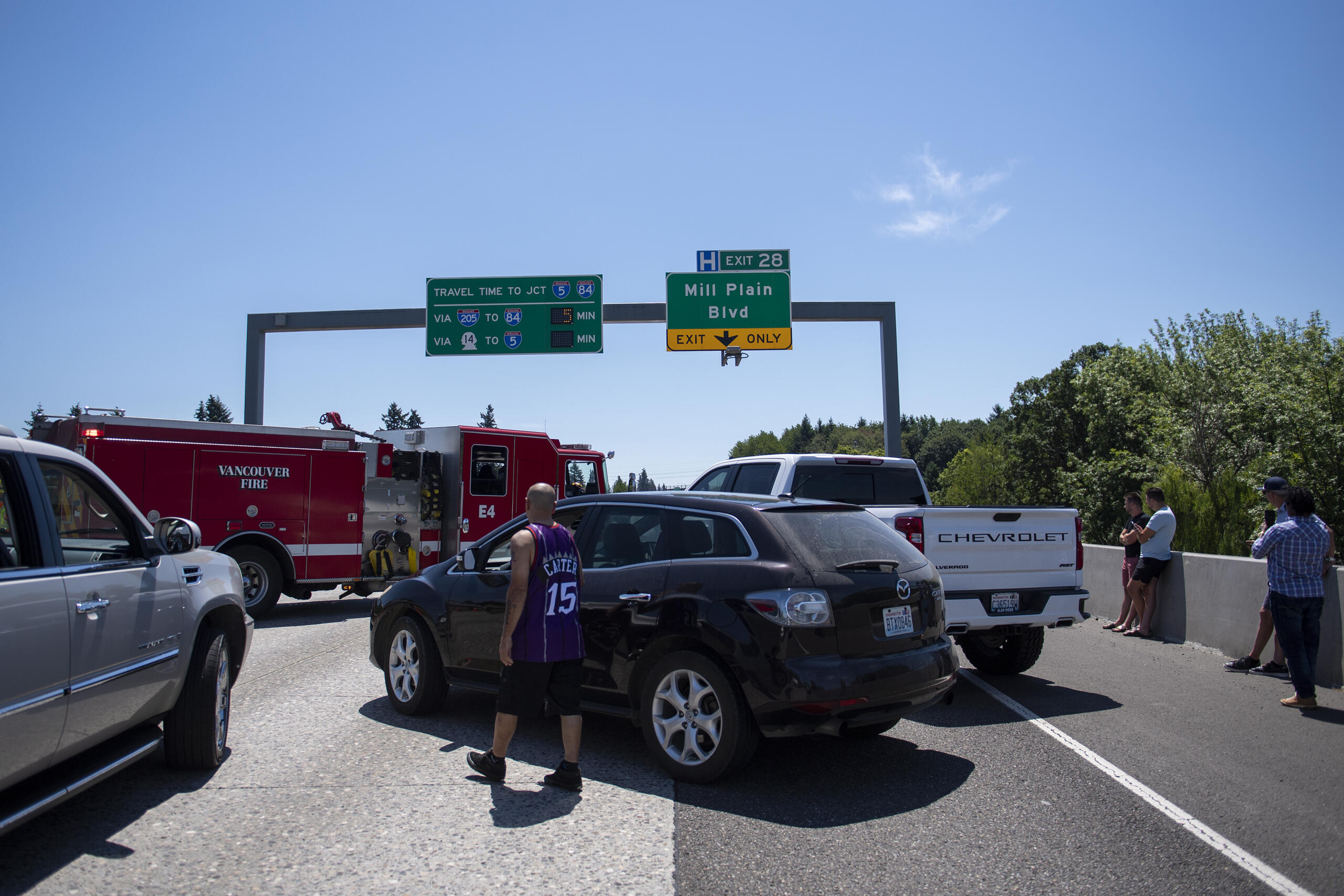 Stuck motorists survey the scene as they gather in the southbound Interstate 205 near the Mill Plain Boulevard exit on Friday afternoon, July 9, 2021.