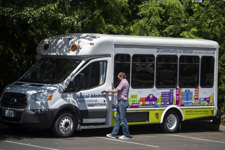 Michael Kelly, transportation services manager for Community in Motion, steps into one of two newly decorated vehicles Thursday afternoon.