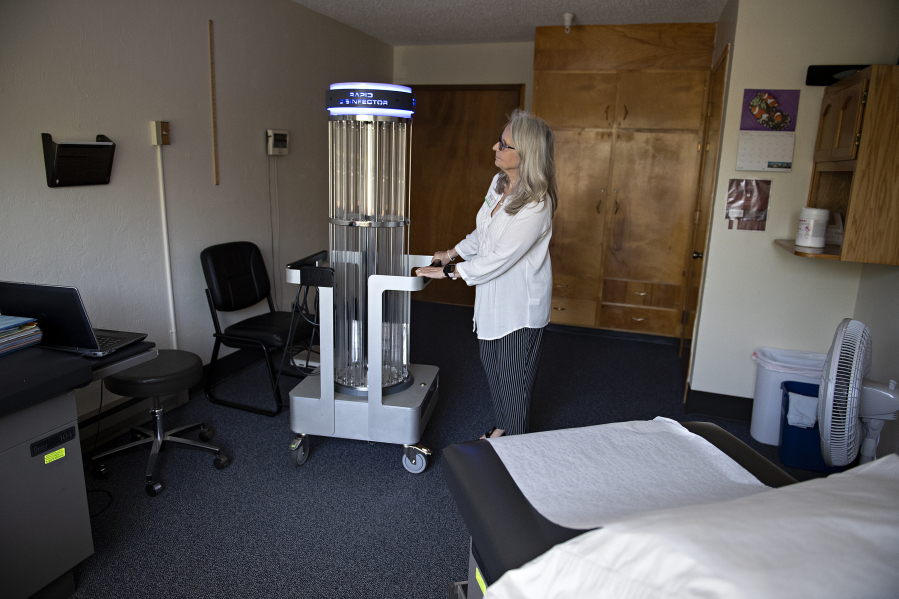 Sue Neal, executive director of Battle Ground HealthCare, looks over a rapid disinfector ultraviolet light sterilizer that helps fight COVID-19. The free clinic provides a range of health care services, which will be expanded at the new location.