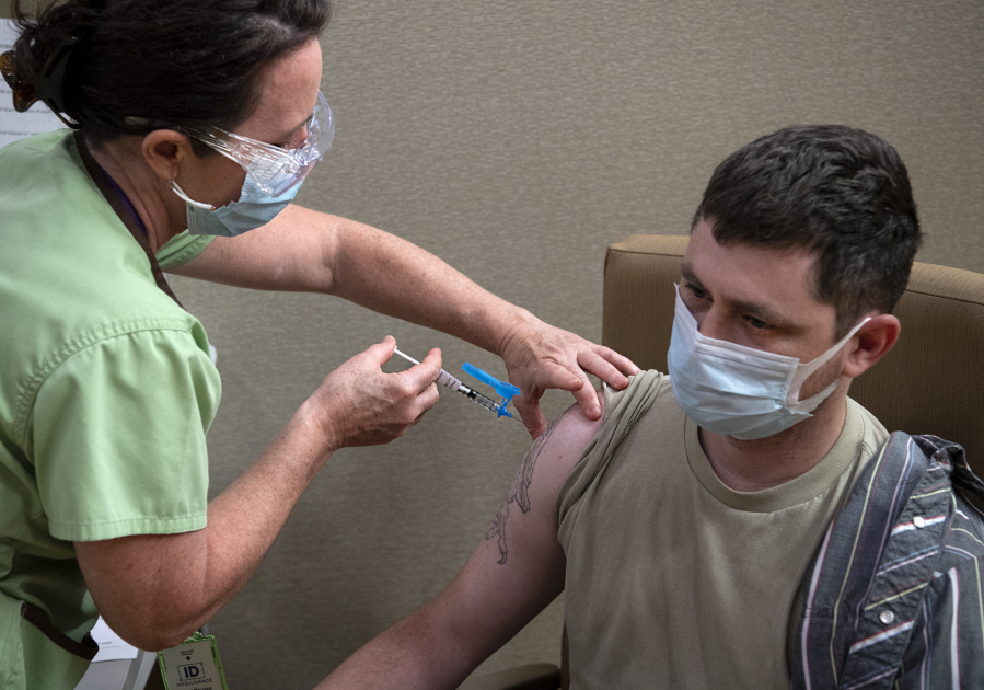 Veterans Affairs registered nurse Jennifer Graham gives Army veteran Nathan Gegenheiner the COVID-19 vaccine. Gegenheiner had to postpone his vaccination until he finished cancer treatment.