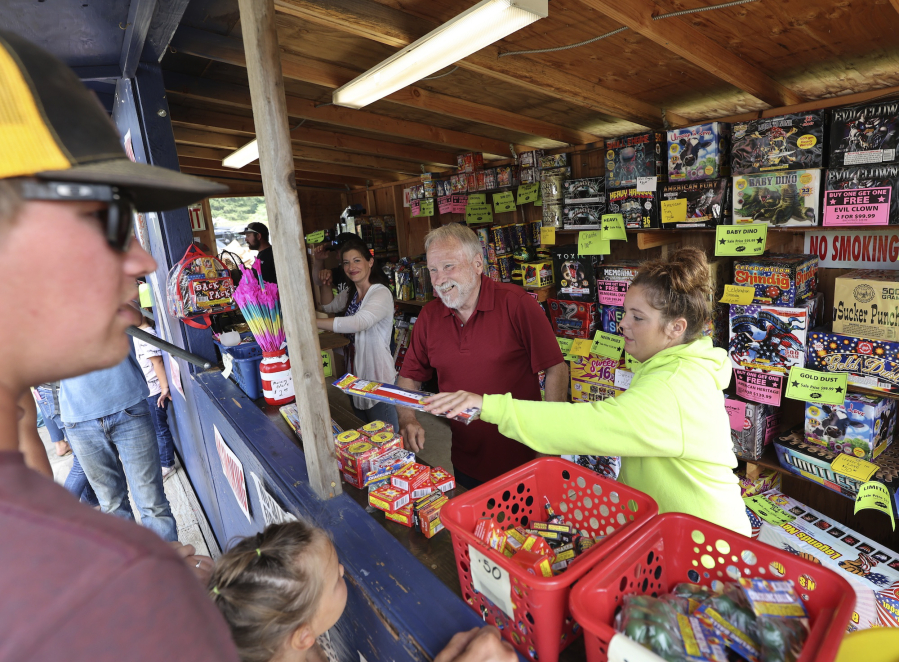 Les Clifton, left, and Arieonna Falander, right, help Yacolt customers buy fireworks to celebrate the Fourth of July, despite fireworks being banned everywhere else in Clark County for their fire risk. Clifton anticipates this year being the most successful year of sales.