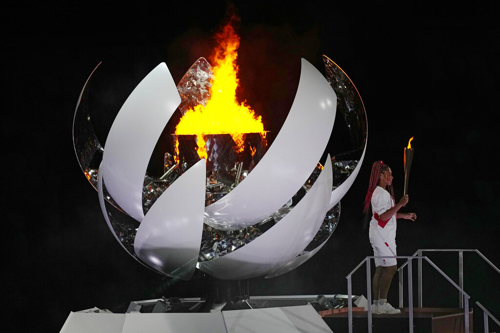 Naomi Osaka stands beside the Olympic flame after lighting it during the opening ceremony in the Olympic Stadium at the 2020 Summer Olympics, Friday, July 23, 2021, in Tokyo, Japan. (AP Photo/David J.