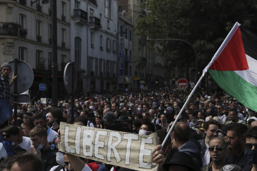 Protestors hold up a banner which reads 'freedom' in French during a demonstration in Paris, France, Saturday, July 31, 2021. Demonstrators gathered in several cities in France on Saturday to protest against the COVID-19 pass, which grants vaccinated individuals greater ease of access to venues.