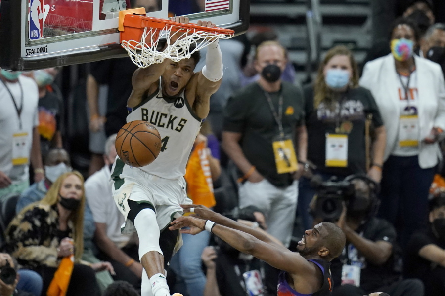 Milwaukee Bucks forward Giannis Antetokounmpo, top, dunks over Phoenix Suns guard Chris Paul during the second half of Game 5 of basketball's NBA Finals, Saturday, July 17, 2021, in Phoenix. (AP Photo/Ross D.