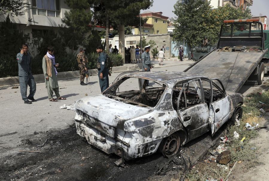 Security personnel inspect a damaged vehicle where rockets were fired from in Kabul, Afghanistan, Tuesday, July 20, 2021. At least three rockets hit near the presidential palace on Tuesday shortly before Afghan President Ashraf Ghani was to give an address to mark the Muslim holiday of Eid-al-Adha.
