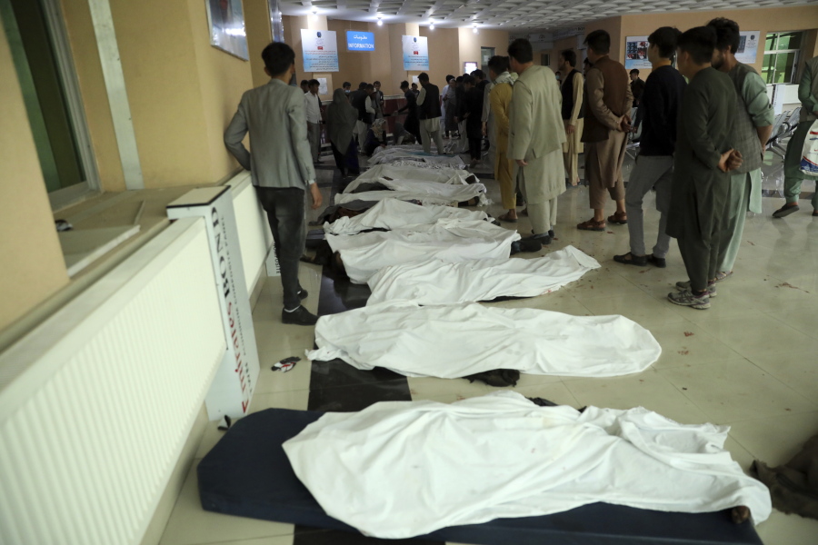 FILE - In this May 8, 2021 file photo, Afghan men try to identify the dead bodies at a hospital after a bomb explosion near a school west of Kabul, Afghanistan. In a report released Monday, July 26, 2021, the United Nations said that more women and children were killed and wounded in Afghanistan in the first half of 2021 than in any year since the UN began keeping count in 2009.