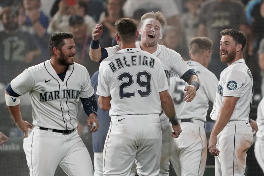 Seattle Mariners' Jarred Kelenic, center, hugs Cal Raleigh (29) after being covered with powder by teammates after Kelenic scored the winning run on a wild pitch during the ninth inning of the team's baseball game against the Oakland Athletics, Saturday, July 24, 2021, in Seattle. The Mariners won 5-4. (AP Photo/Ted S.