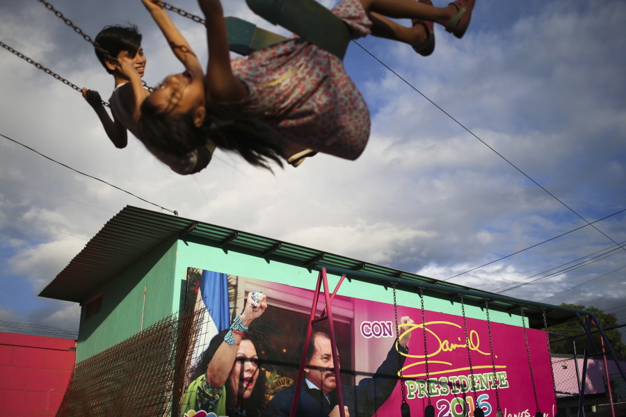 FILE - In this Nov. 4, 2016 file photo, children swing in a park next to an election billboard for President Daniel Ortega and his running mate, his wife, Rosario Murillo in Managua, Nicaragua. In June 2021, amid a weekslong clampdown to obliterate nearly every hint of opposition, Ortega ordered the arrest of Hugo Torres, a revered guerrilla in the fight against right-wing dictator Anastasio Somoza. In 1974, Torres had taken a group of top officials hostage, then traded them for the release of imprisoned comrades, among them, Daniel Ortega.