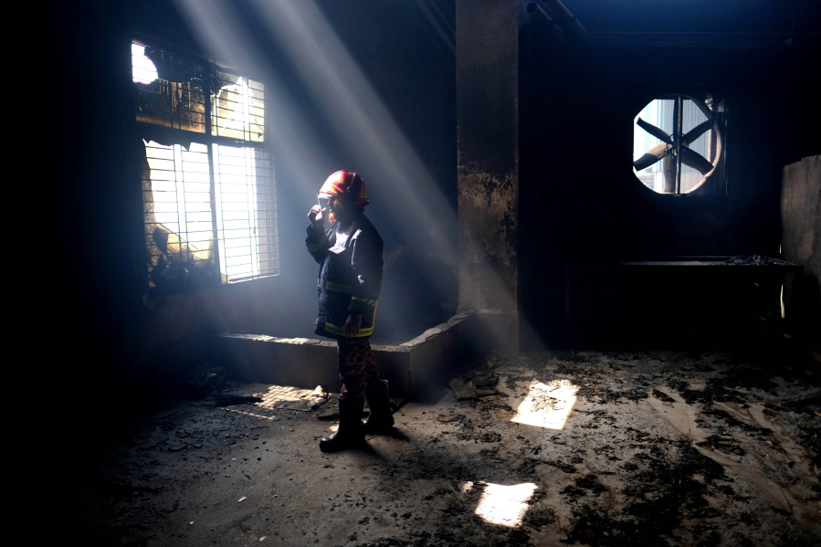 A firefighter communicates with his colleagues on a walkie talkie inside the burnt food and beverage factory in Rupganj, outside Dhaka, Bangladesh, Friday, July 9, 2021. At least 52 people died in a huge blaze that engulfed a food and beverage factory outside Bangladesh's capital, fire officials said Friday, in the latest industrial disaster to hit the South Asian nation.
