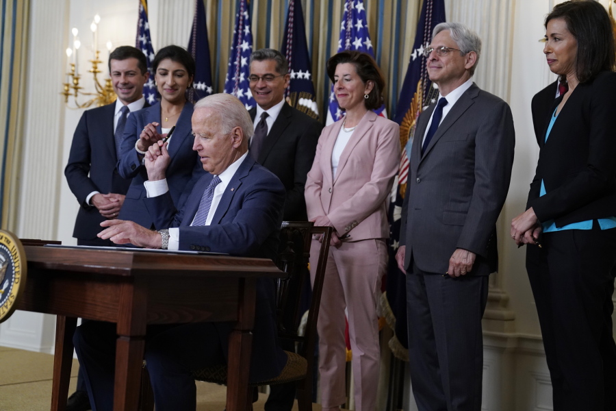 President Joe Biden hands out a pen after signing an executive order aimed at promoting competition in the economy, in the State Dining Room of the White House, Friday, July 9, 2021, in Washington. Standing from left, Transportation Secretary Pete Buttigieg, Lina Khan, Chair of the Federal Trade Commission, Health and Human Services Secretary Xavier Becerra, Commerce Secretary Gina Raimondo, Attorney General Merrick Garland, National Economic Council director Brian Deese, obscured, and Jessica Rosenworcel, Acting Chairwoman of the Federal Communications Commission.