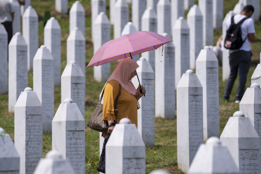 A woman visits the memorial cemetery in Potocari near Srebrenica, Bosnia, Sunday, July 11, 2021. Bosnia is marking the 26th anniversary of the Srebrenica massacre, the only episode of its 1992-95 fratricidal war that has been declared a genocide by international and national courts. The brutal execution of more than 8,000 Muslim Bosniaks by Bosnian Serb troops is being commemorated by a series of events Sunday.