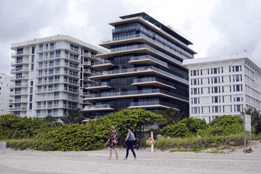 Beachgoers walk by the beach entrance to the Arte by Antonio Citterio condominium, center, Tuesday, June 29, 2021, in Surfside, Fla. Jared Kushner and Ivanka Trump rent an apartment at Arte while their home is under construction at nearby Indian Creek Village.