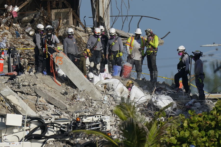 A team works to extricate remains as search and rescue personnel look on, atop the rubble at the Champlain Towers South condo building where scores of people remain missing more than a week after it partially collapsed, Friday, July 2, 2021, in Surfside, Fla.