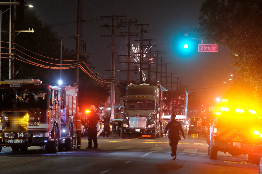 Fireworks continue to fill the skyline as emergency personnel respond to the explosion of an armored Los Angeles Police Department tractor-trailer in South Los Angeles Wednesday evening, June 30, 2021. A cache of illegal fireworks seized at a South Los Angeles home exploded, damaging nearby homes and cars and causing injuries, authorities said. (AP Photo/Ringo H.W.