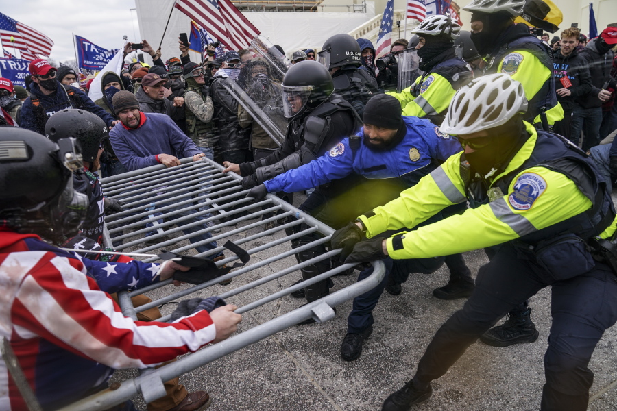 FILE - In this Jan. 6, 2021, file photo violent insurrectionists loyal to President Donald Trump hold on to a police barrier at the Capitol in Washington. Months after Donald Trump's supporters besieged the Capitol, the ex-president and his supporters are revising their account of that day.