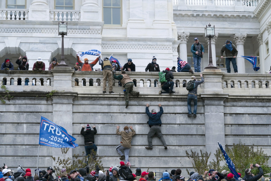 FILE - In this Jan. 6, 2021, file photo, violent insurrectionists loyal to President Donald Trump scale the west wall of the the U.S. Capitol in Washington. Two Seattle police officers who were in Washington, D.C., during the Jan. 6 insurrection were illegally trespassing on Capitol grounds while rioters stormed the building, but lied about their actions, a police watchdog said in a report released Thursday, July 8, 2021.