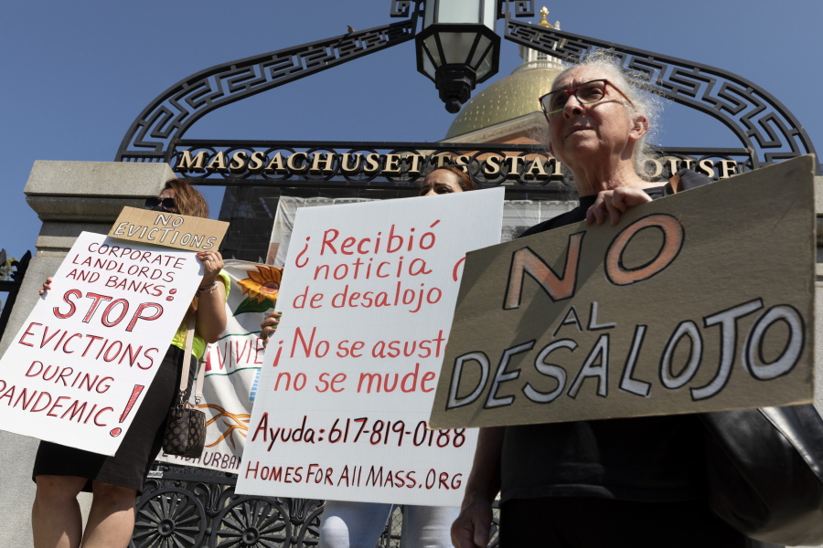 People from a coalition of housing justice groups hold signs protesting evictions during a news conference outside the Statehouse, Friday, July 30, 2021, in Boston.