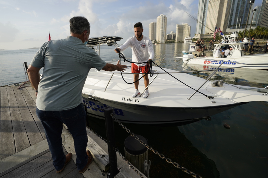 Ramon Saul Sanchez, left, leader of the nonprofit group Movimiento Democracia that launched several flotillas in the past, helps boater Julio Gonzalez tie up his boat, Friday, July 23, 2021, in downtown Miami. A small group of Cuban Americans launched motorboats from Miami to their homeland to show support for people experiencing hardships on the island. Five boats left the Bayside marina just before 8 a.m. Friday. They plan to refuel in Key West before heading into the Florida Straits.