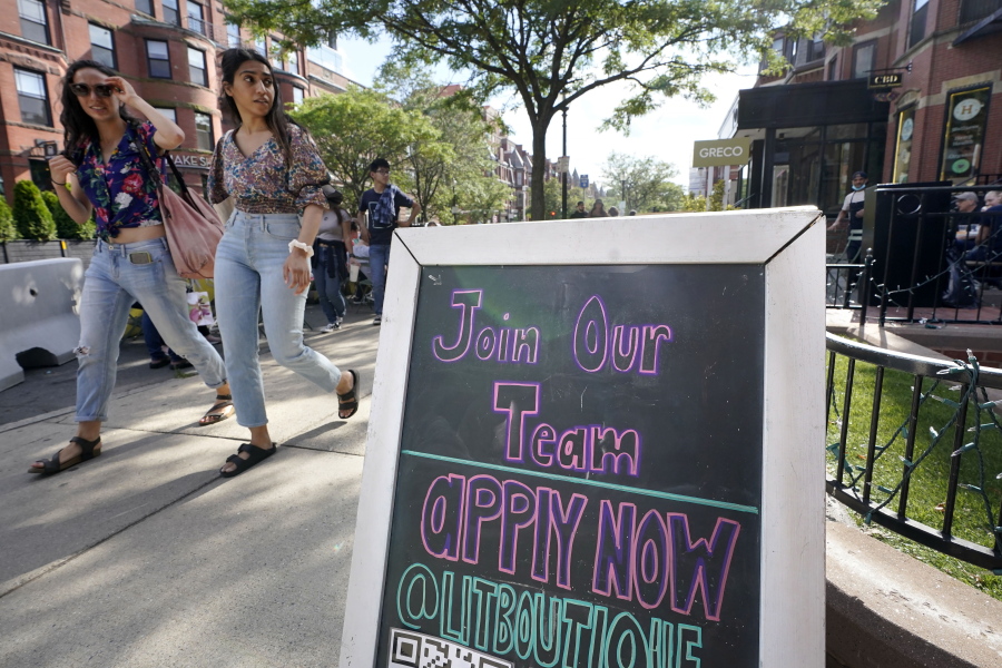 Pedestrians walk past a sign inviting people to apply for employment at a shop in Boston's fashionable Newbury Street neighborhood, Monday, July 5, 2021.  As the U.S. economy bounds back with unexpected speed from the pandemic recession and customer demand intensifies, high school-age kids are filling jobs that older workers can't -- or won't.