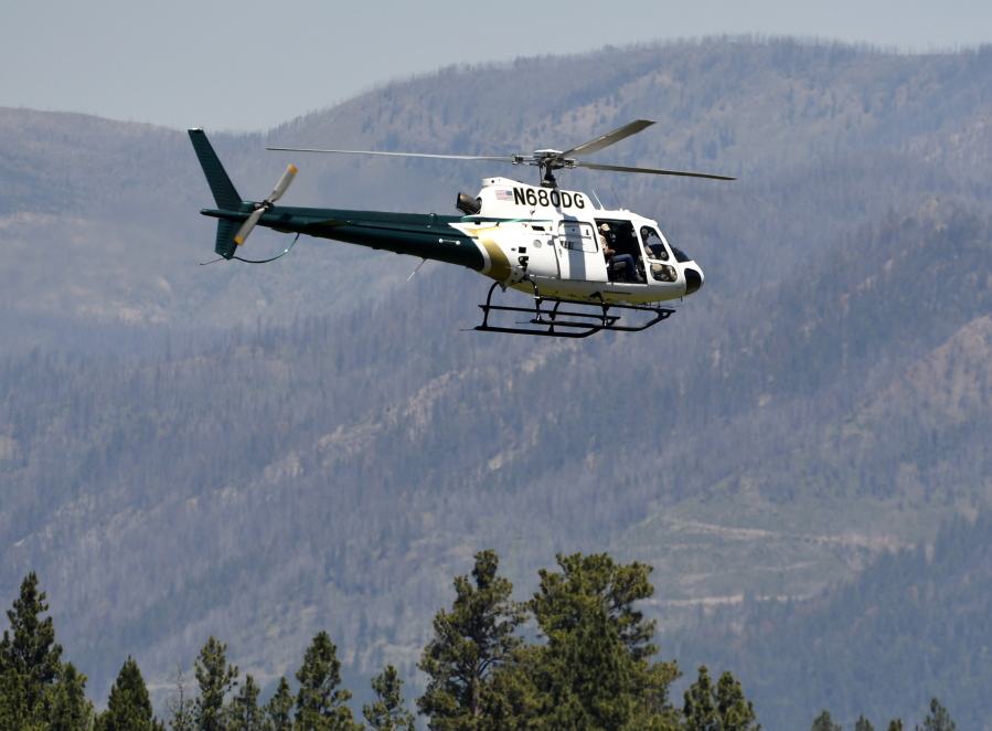 A helicopter from Montana Fish, Wildlife and Parks flies around the Ovando, Mont., area on Tuesday, July 6, 2201, in search of a bear that killed a camper early that morning. The search for the bear continued Wednesday.