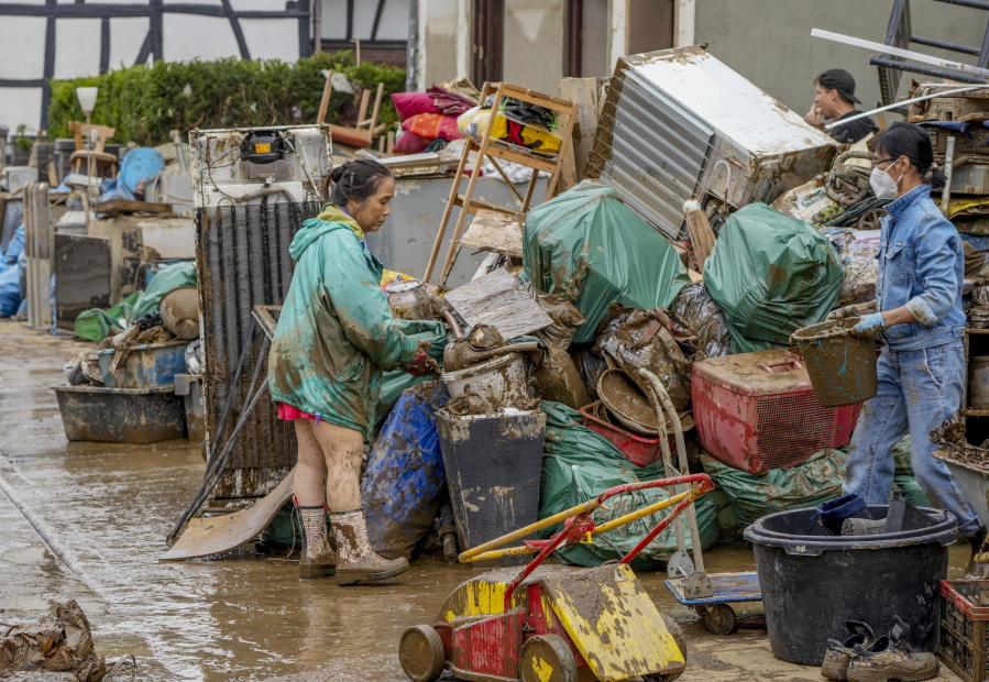 People clean their homes from mud and debris in Bad Neuenahr-Ahrweiler, Germany, Saturday, July 17, 2021. Due to strong rainfall, the Ahr river went over its banks and flooded big parts of the town.