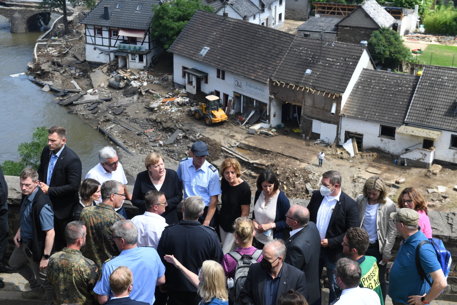 German Chancellor Angela Merkel, rear third left, and the Governor of the German state of Rhineland-Palatinate, Malu Dreyer, rear fifth left, are seen on a bridge in Schuld, western Germany, Sunday, July 18, 2021 during their visit in the flood-ravaged areas to survey the damage and meet survivors. After days of extreme downpours causing devastating floods in Germany and other parts of western Europe the death toll has risen.