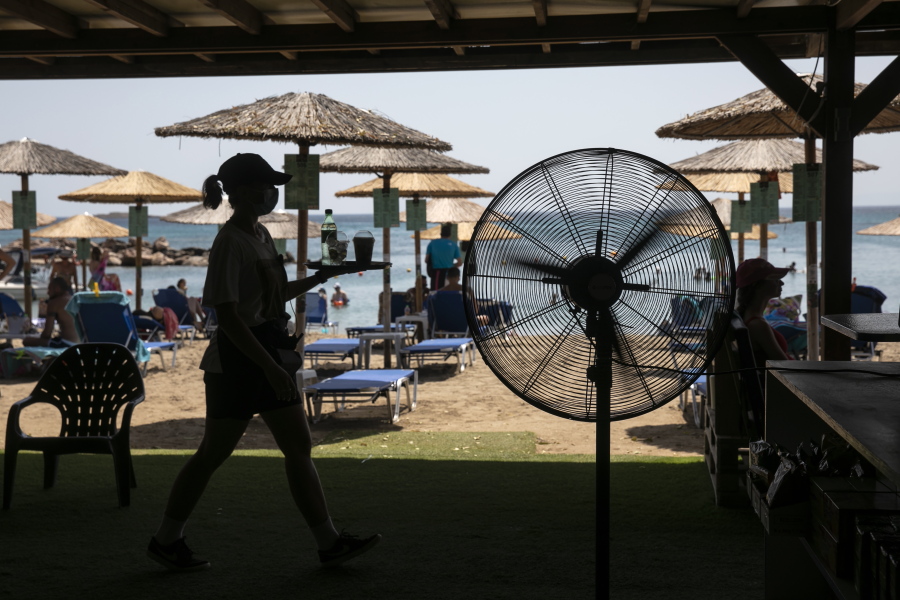 A waitress serves refreshments at a beach bar of Lagonissi village, a few miles southwest of Athens, on Thursday, July 29, 2021. One of the most severe heat waves recorded since 1980s scorched southeast Europe on Thursday, sending residents flocking to the coast, public fountains and air-conditioned locations to find some relief, with temperatures rose above 40 C (104 F) in parts of Greece and across much of the region.
