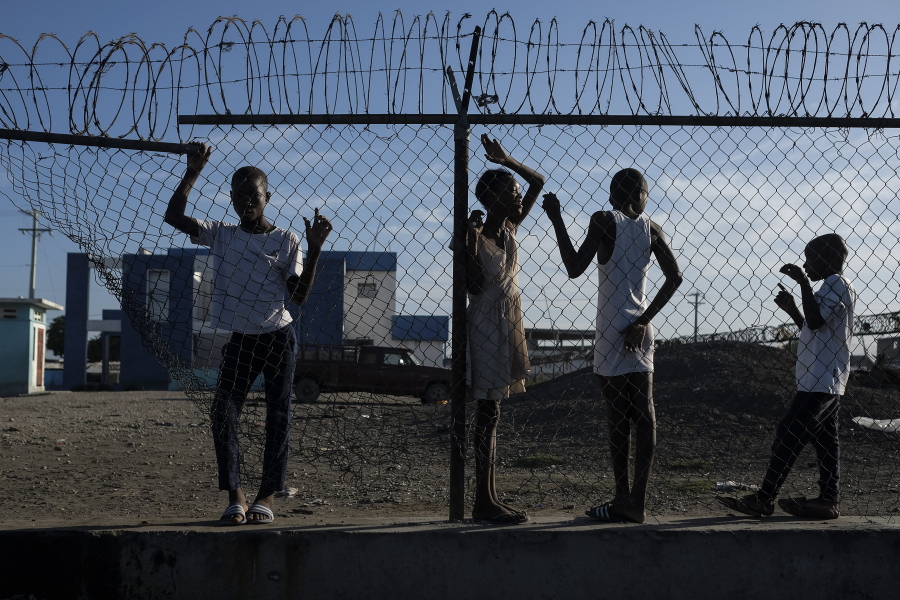 Youths stand at a gate along the seashore in the La Saline neighborhood of Port-au-Prince, Haiti, Monday, July 19, 2021. The country of more than 11 million people are still reeling from the July 7 killing of President Jovenel Moise.