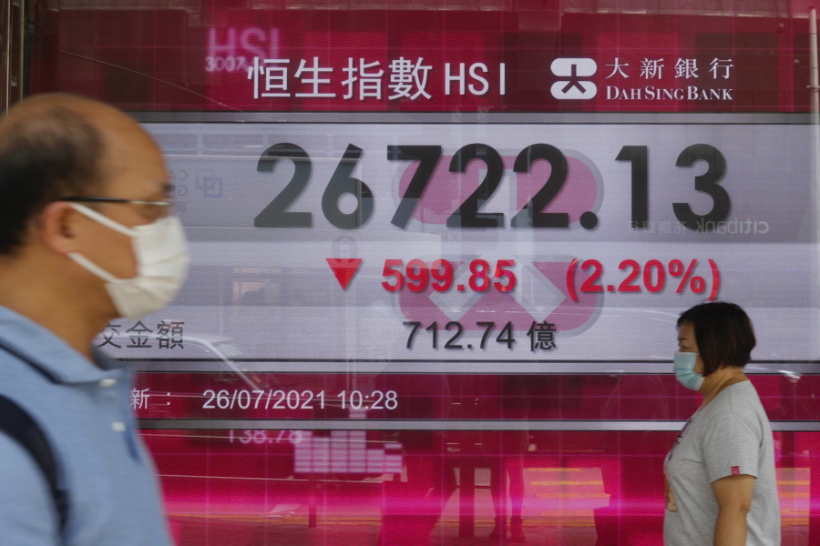 People walk past a bank's electronic board showing the Hong Kong share index at Hong Kong Stock Exchange Monday, July 26, 2021. Asian shares opened mixed on Monday after stocks rallied to records on Wall Street, with the Dow Jones Industrial Average closing above the 35,000 level for the first time.
