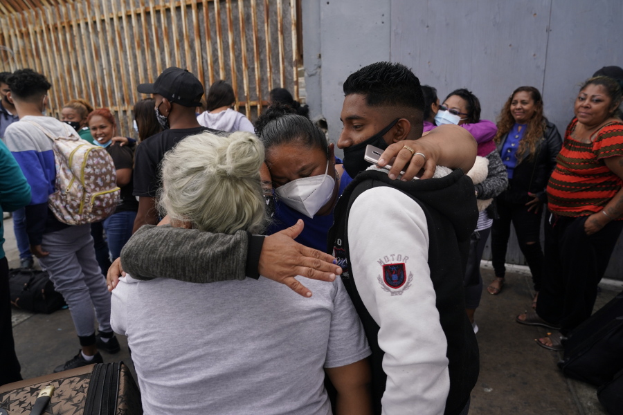 FILE - In this July 5, 2021, file photo, Alex Cortillo, right, of Honduras gets a hug from Erika Valladares Ponce, of Honduras, center, and others, as he waits to cross into the United States to begin the asylum process in Tijuana, Mexico. Two nongovernmental organizations said Friday, July 30, 2021, that they are ending cooperation with the Biden Administration to identify the most vulnerable migrants waiting in Mexico to be admitted to the United States to seek asylum.