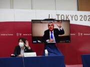International Olympic Committee (IOC) president Thomas Bach (on-screen) and Tokyo 2020 president Seiko Hashimoto, left, wave at the beginning of the five-party meeting in Tokyo, Thursday, July 8, 2021.