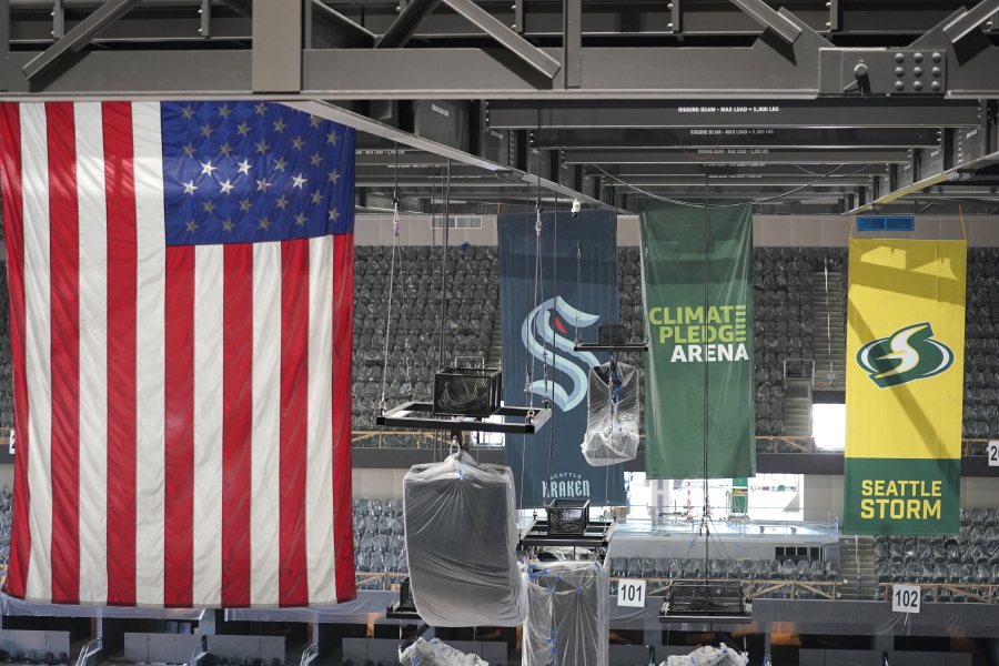 United States and team flags hang in the rafters of the Climate Pledge Arena during a media tour of the facility on Monday, July 12, 2021, in Seattle. The NHL expansion team Seattle Kraken will begin to fill out its roster with the expansion draft on Wednesday, July 21, 2021.  (AP Photo/Ted S.