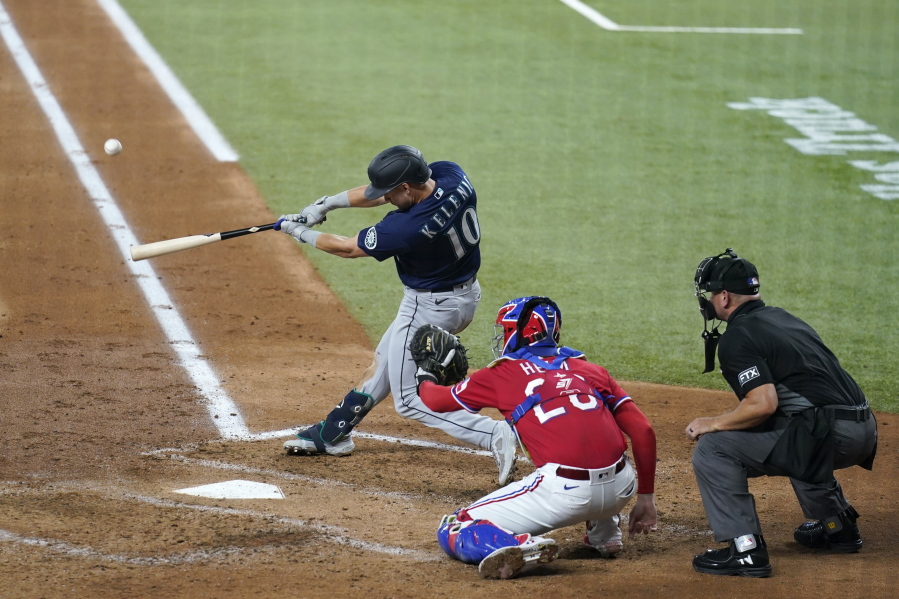 Seattle Mariners' Jarred Kelenic (10) connects for a three-run home run in front ot Texas Rangers' Jonah Heim and umpire Scott Barry during the third inning of a baseball game in Arlington, Texas, Friday, July 30, 2021.