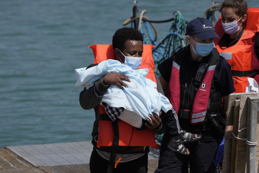 A man and a child thought to be migrants are disembarked from a British border force vessel in Dover, south east England, Thursday, July 22, 2021. The number of undocumented migrants reaching Britain in small boats this year has surpassed the total for all of 2020, as people smugglers take advantage of good weather to cross the English Channel from France.